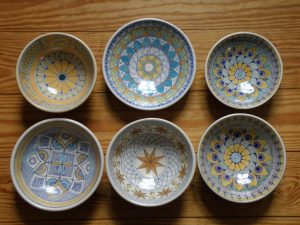 Photo of six pottery bowls with a geometric designs in blue and yellow colors by Steinberg.