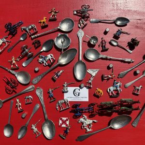 Photo of a table from above covered with an assortment of silver spoons and vintage toys by Georgia Colony Smiths