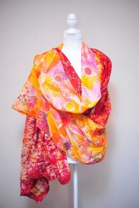 Photo of a patterned red and yellow scarf draped on a manikin by Sareshwala