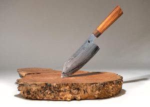 Photo of a knife by Sulmonte balanced on a block of rustic wood.
