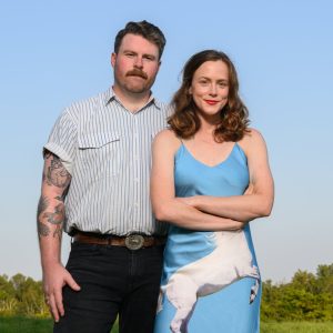 Photo of two members of the Chatham Rabbits musical group standing in field with a blue sky.